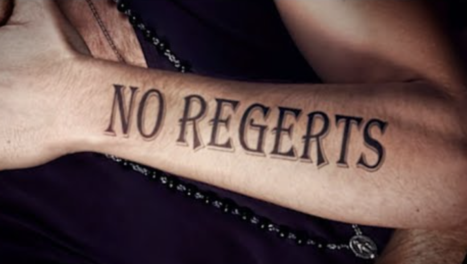 A white person's arm, slightly hairy, with the misspelled phrase "NO REGERTS" tattoed on it